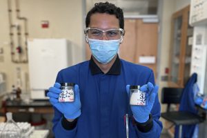 Pedro de Jesús Cruz in a research lab holding containers of solid compound produced in their study.