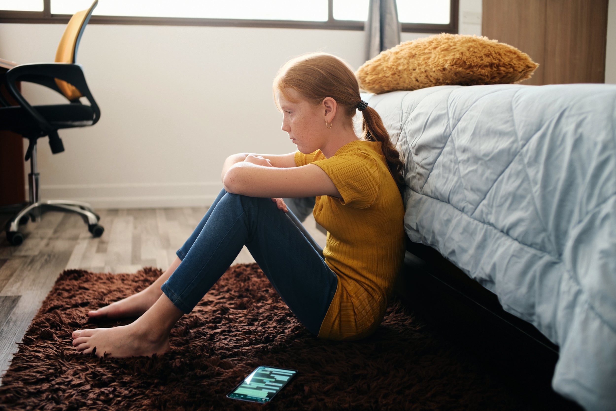 young teen sitting on floor of bedroom