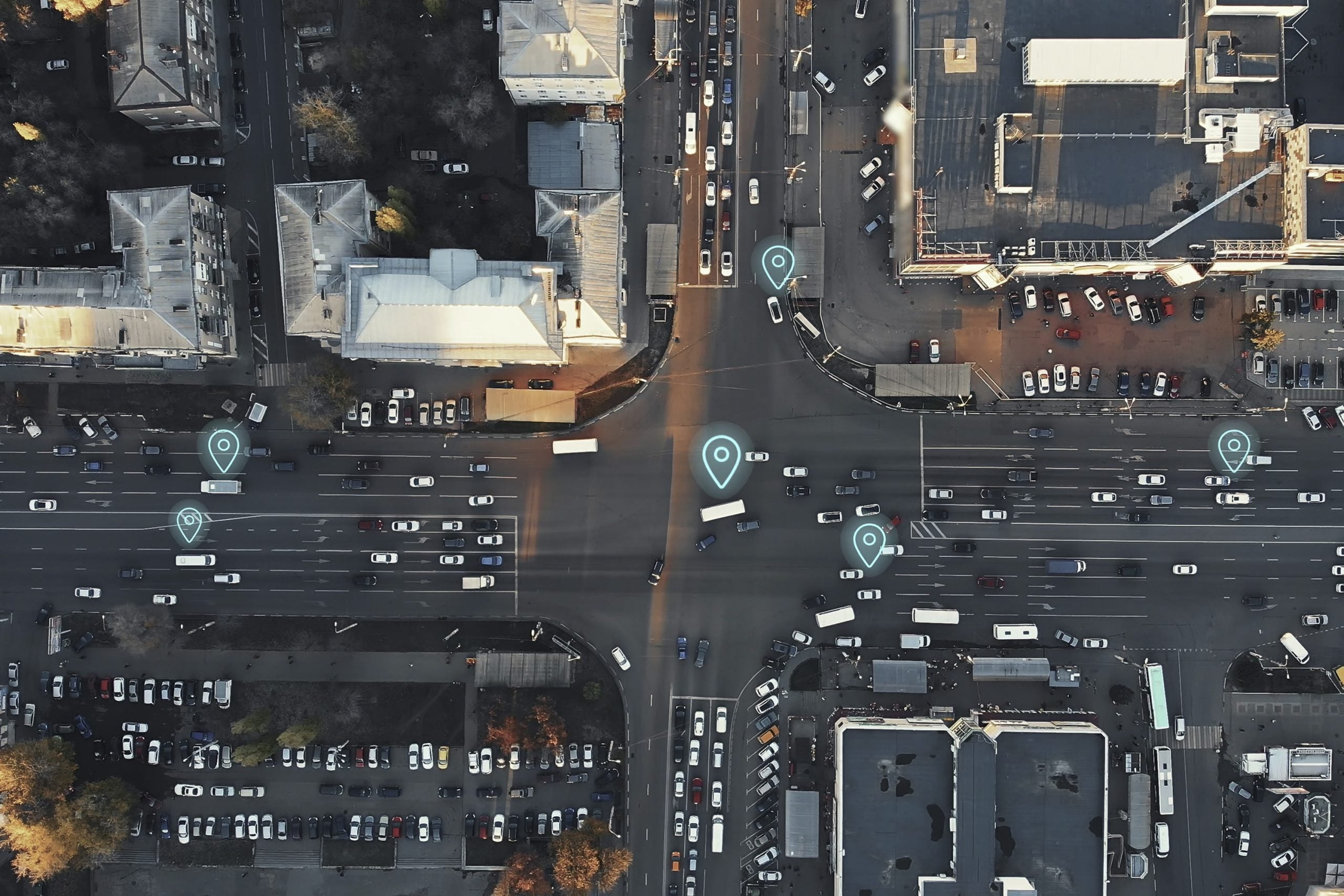 an aerial view of four streets crossing with location icons on a few of the cars