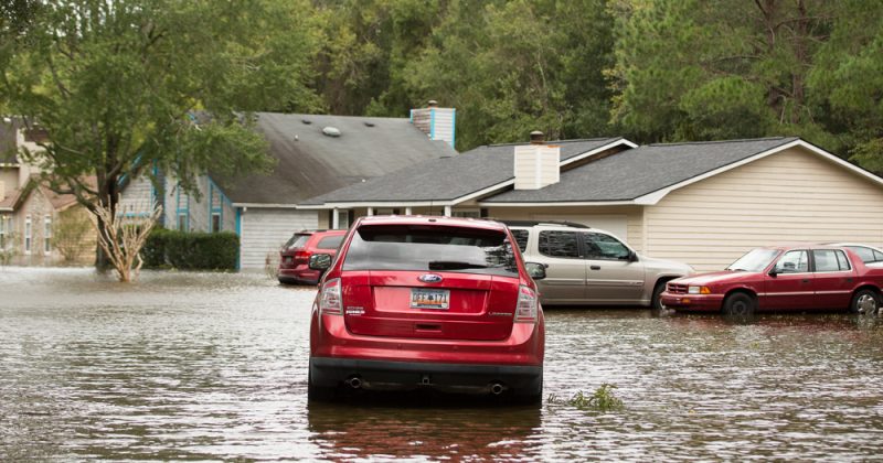 a red SUV drives on a flooded road