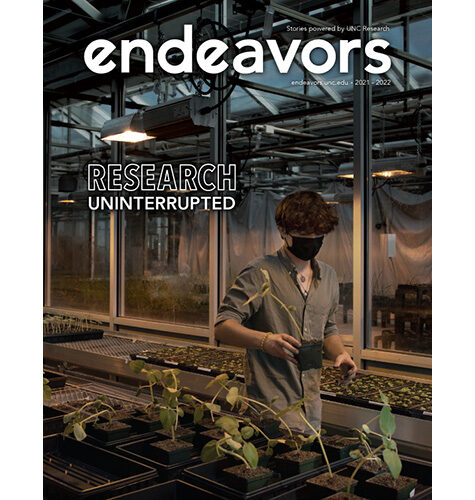 Endeavors 2021-2022 magazine cover, featuring a student researcher working with plants in a greenhouse