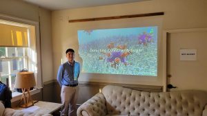 Sanghoon Kim standing next to a projection of his presentation.