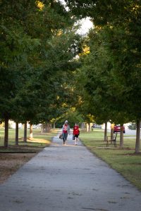 Two students walk to school on a sidewalk.