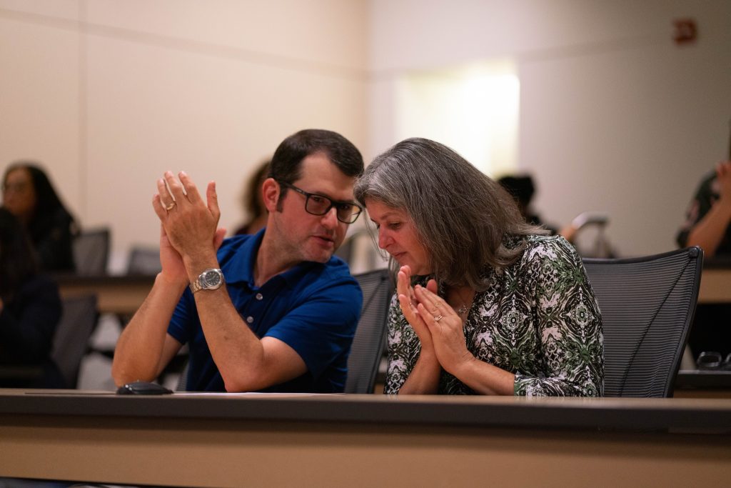 Two people chat as they clap their hands after a presentation.