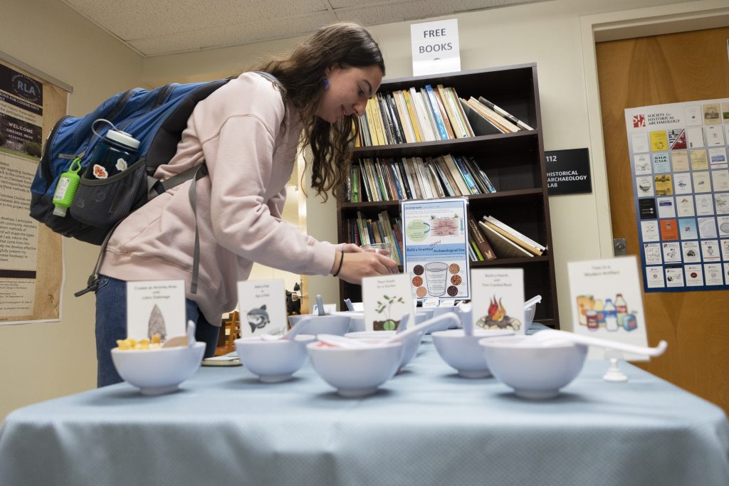 A student stands over bowls of snacks, all labeled as different strata layers.