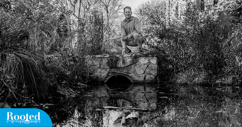 Mike Piehler kneeling next to a small pond.