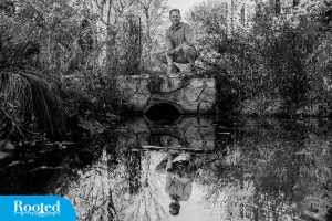  Mike Piehler kneeling next to a small pond 