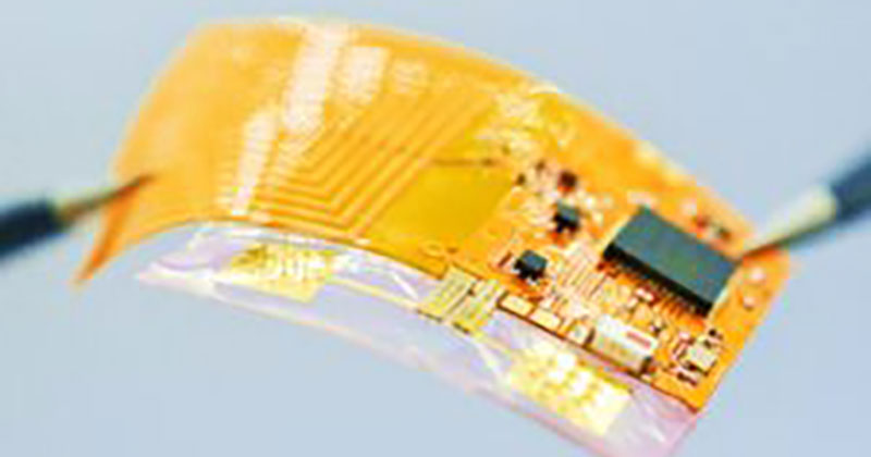 A thin piece of gold material with wiring and a microchip on it.