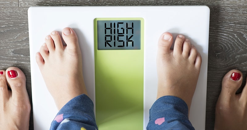 A child's small feet shown standing on a scale that says high risk.