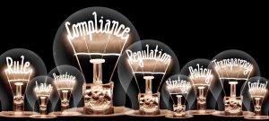 Nine old fashioned looking bulbs with words like compliance and regulation spelled out in the bulb's filament.