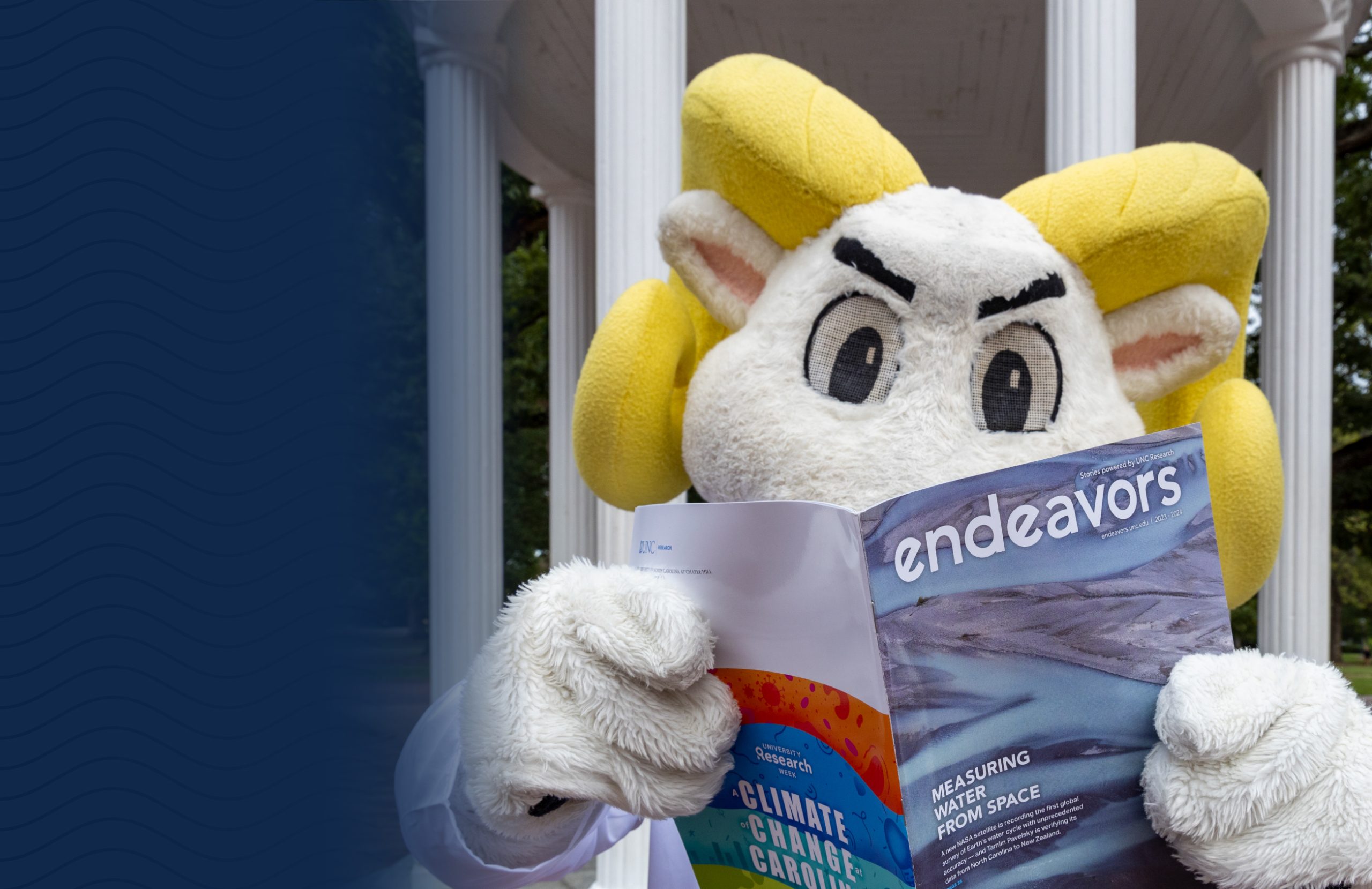 Photo of mascot Rameses reading an endeavors magazine in front of the old well.