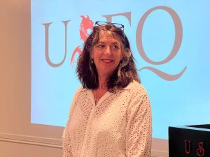 A woman standing in front of a projection screen that says USFQ.