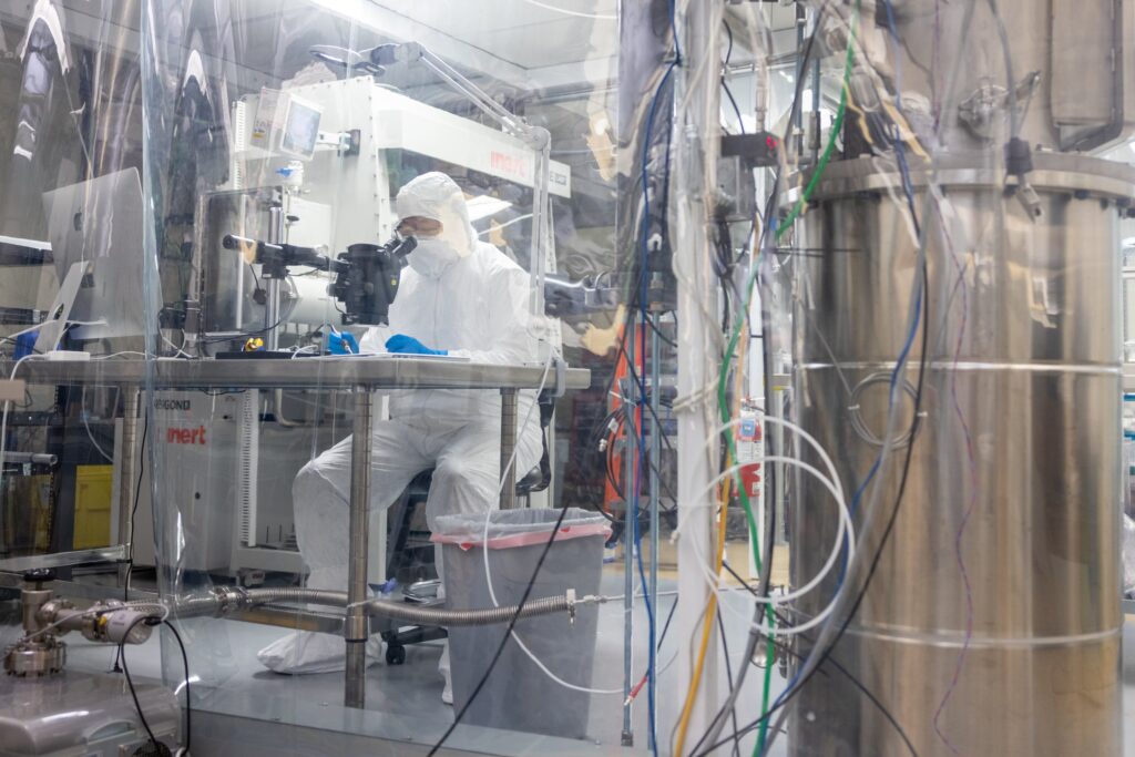 A researcher in full PPE gear around laboratory equipment.