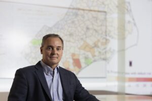Greg Characklis sitting in front of a large map on a wall.