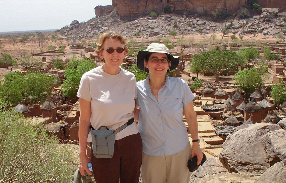 Florence Babb and Victoria Rovine are photographed infront of rocky cliffs of the Dogan region of Mali.