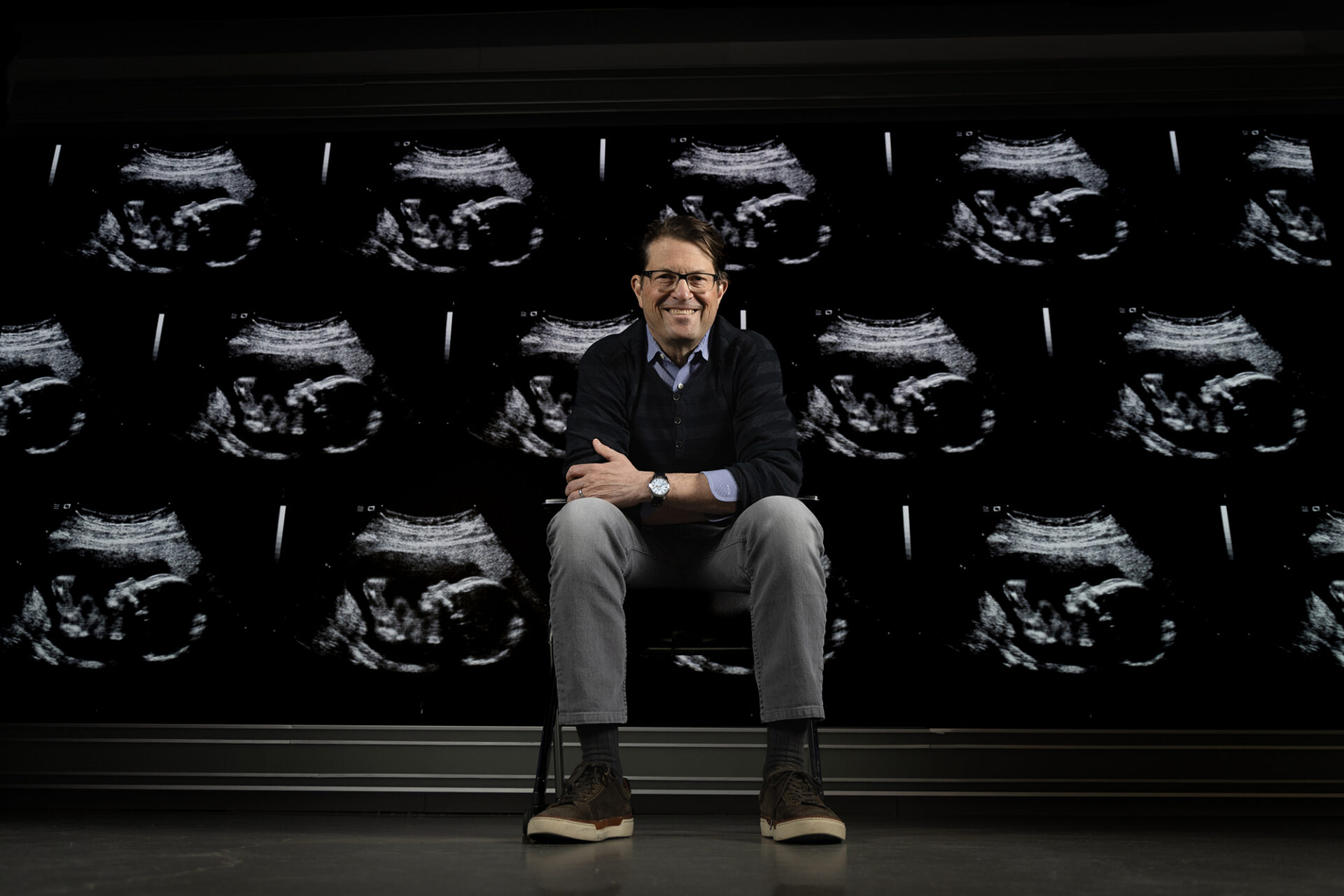 Jeff Stringer in front of a screen covered in pregnancy ultrasounds