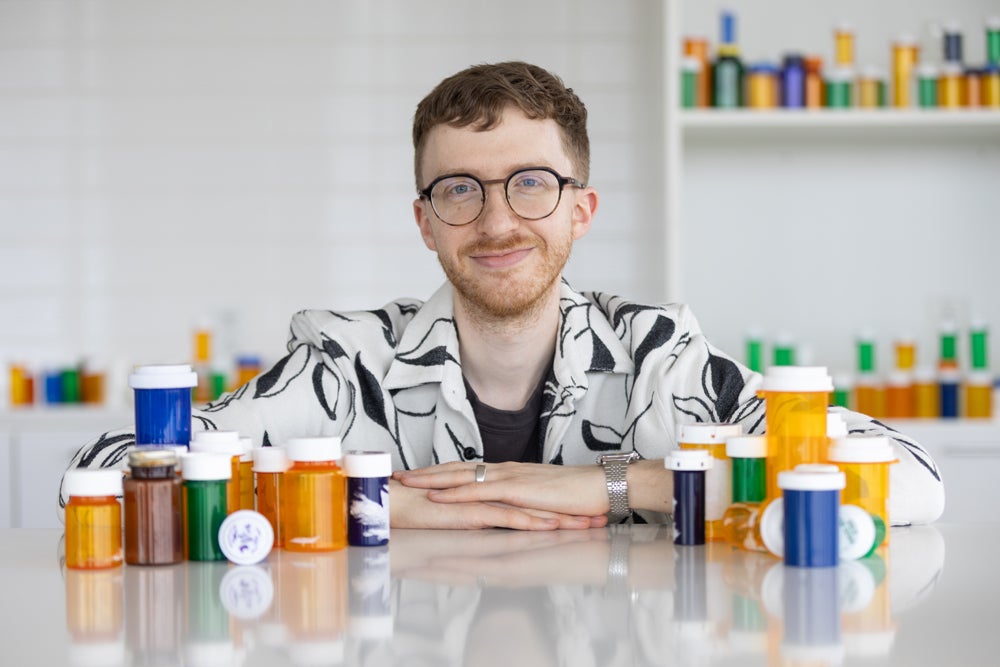 a young man surrounded by colorful prescription medicine bottles