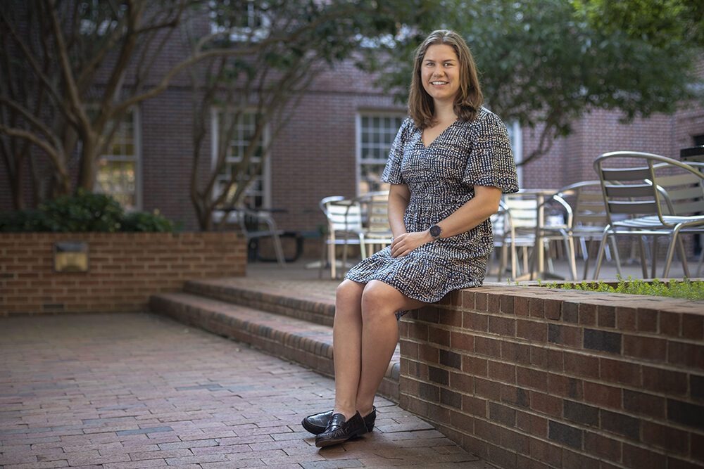 a woman sits on a brick wall in a courtyard