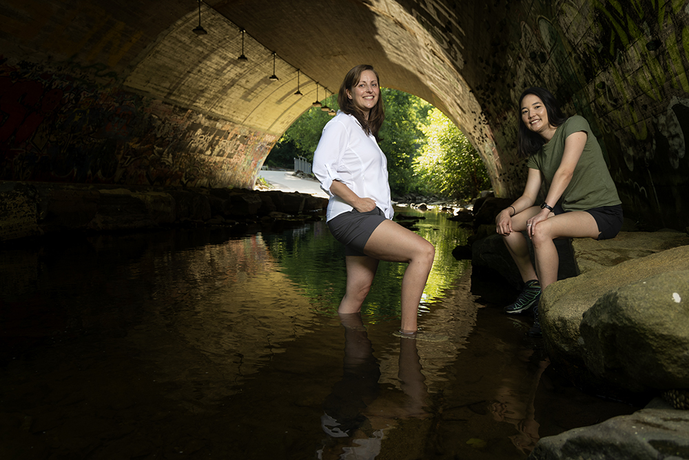 two women stand under a bridge in Bolin Creek