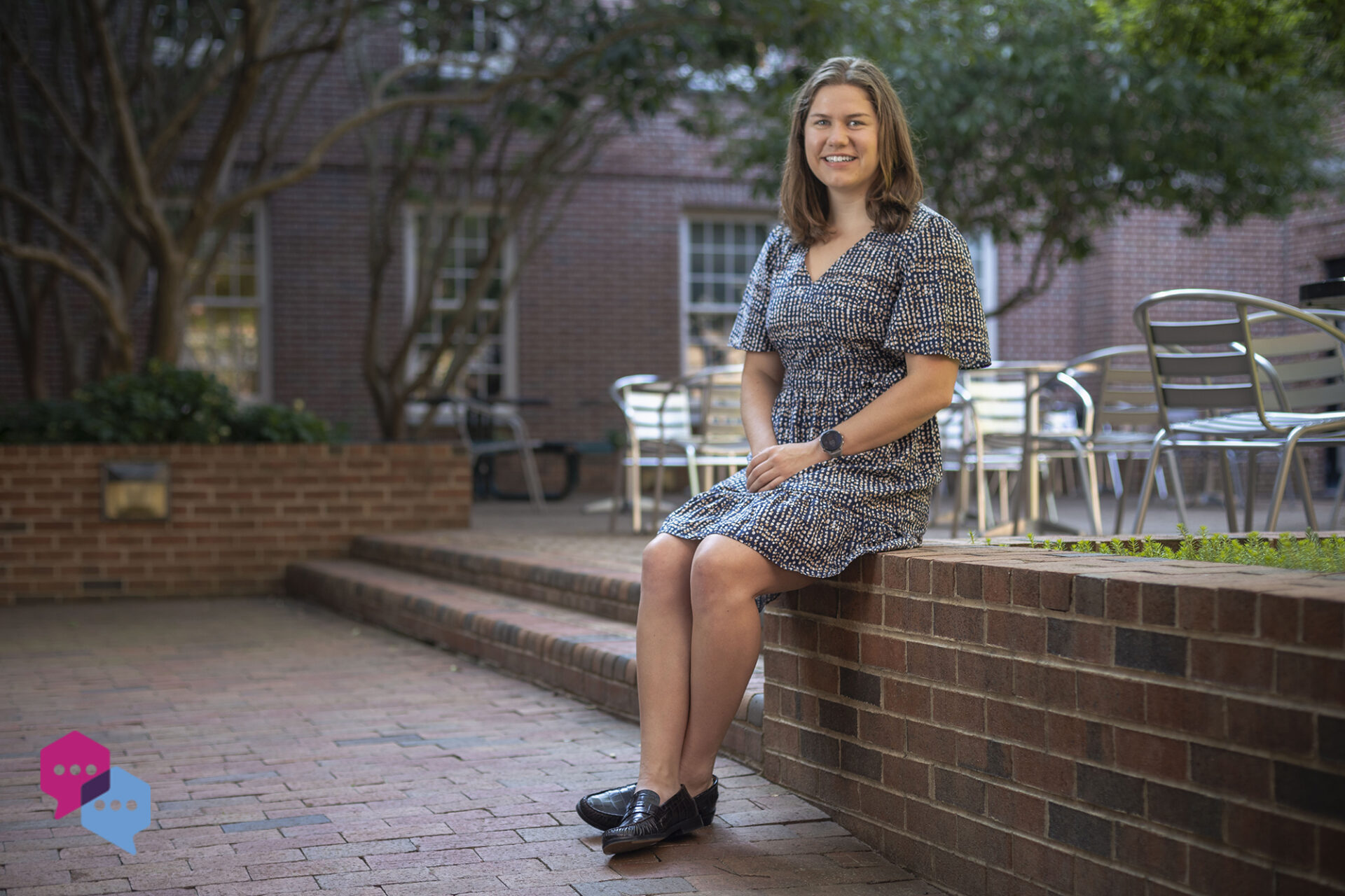 a woman sits on a low wall in a courtyard