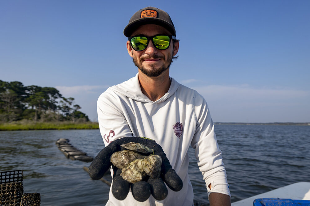 a young man holds out a handful of oysters