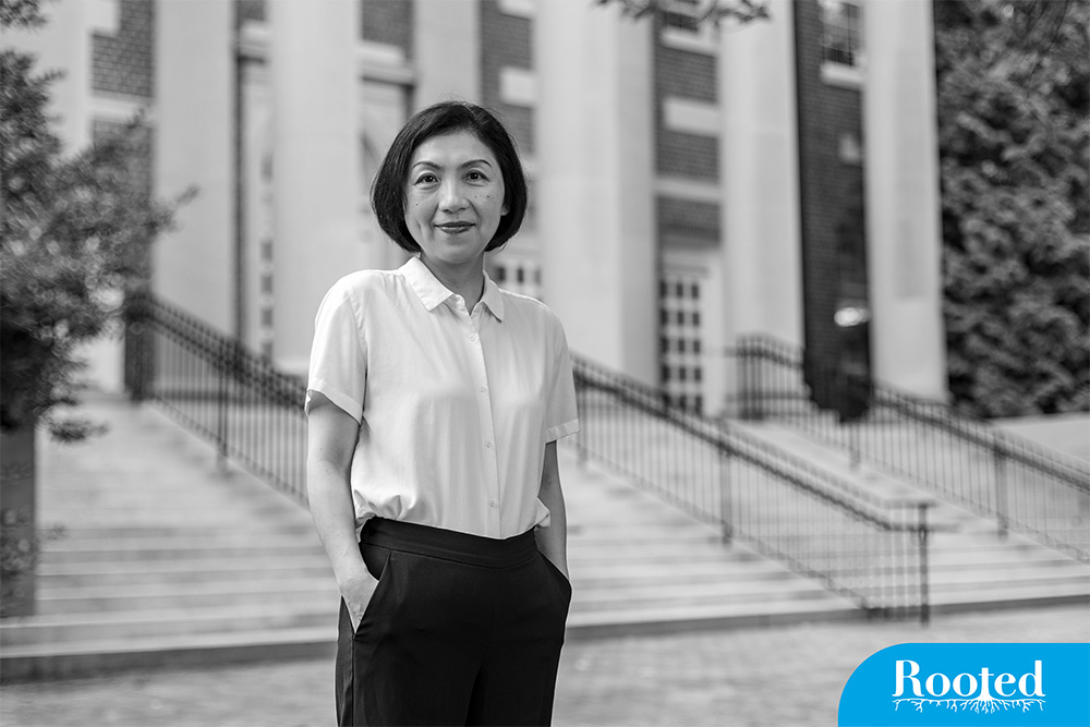 a woman stands in front of a pillared building