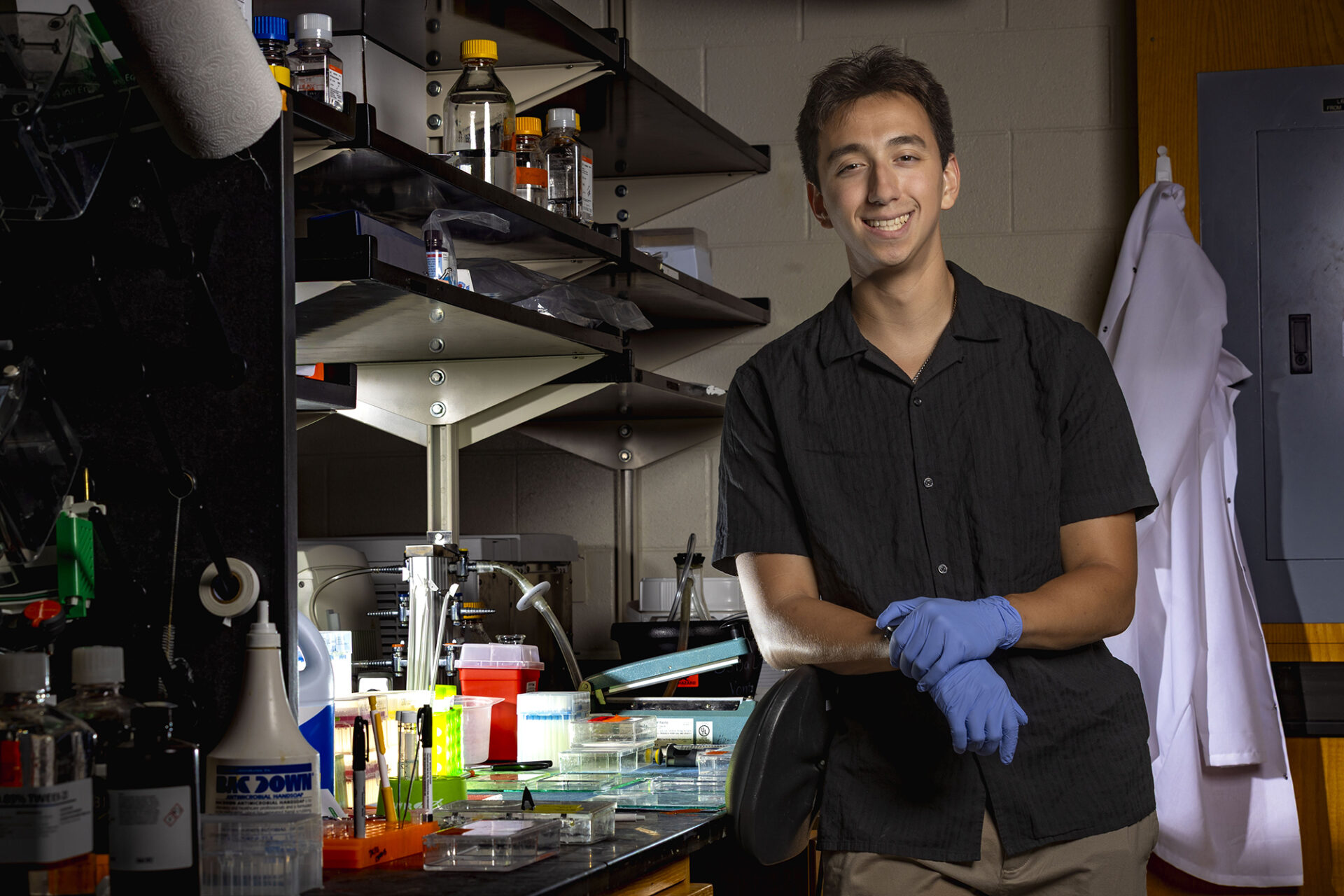 a young man leans against a chair in a lab