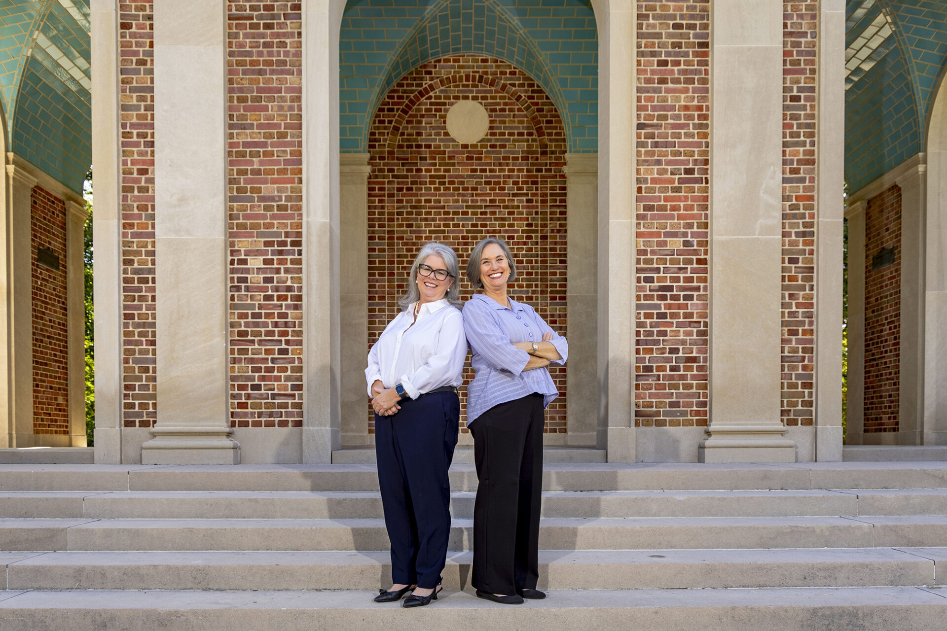 two women stand in front of the Patterson Bell Tower on UNC-Chapel Hill's campus