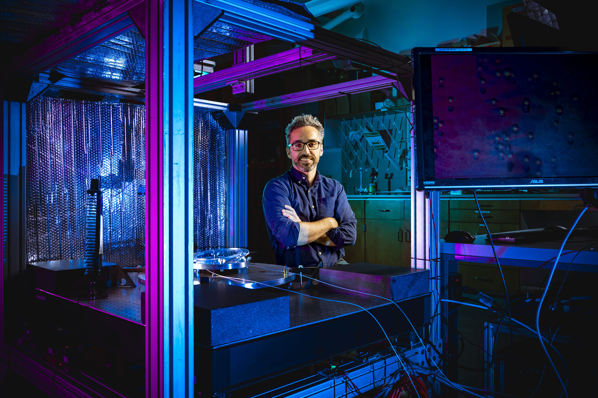 pink and blue lights illuminate a man in a lab