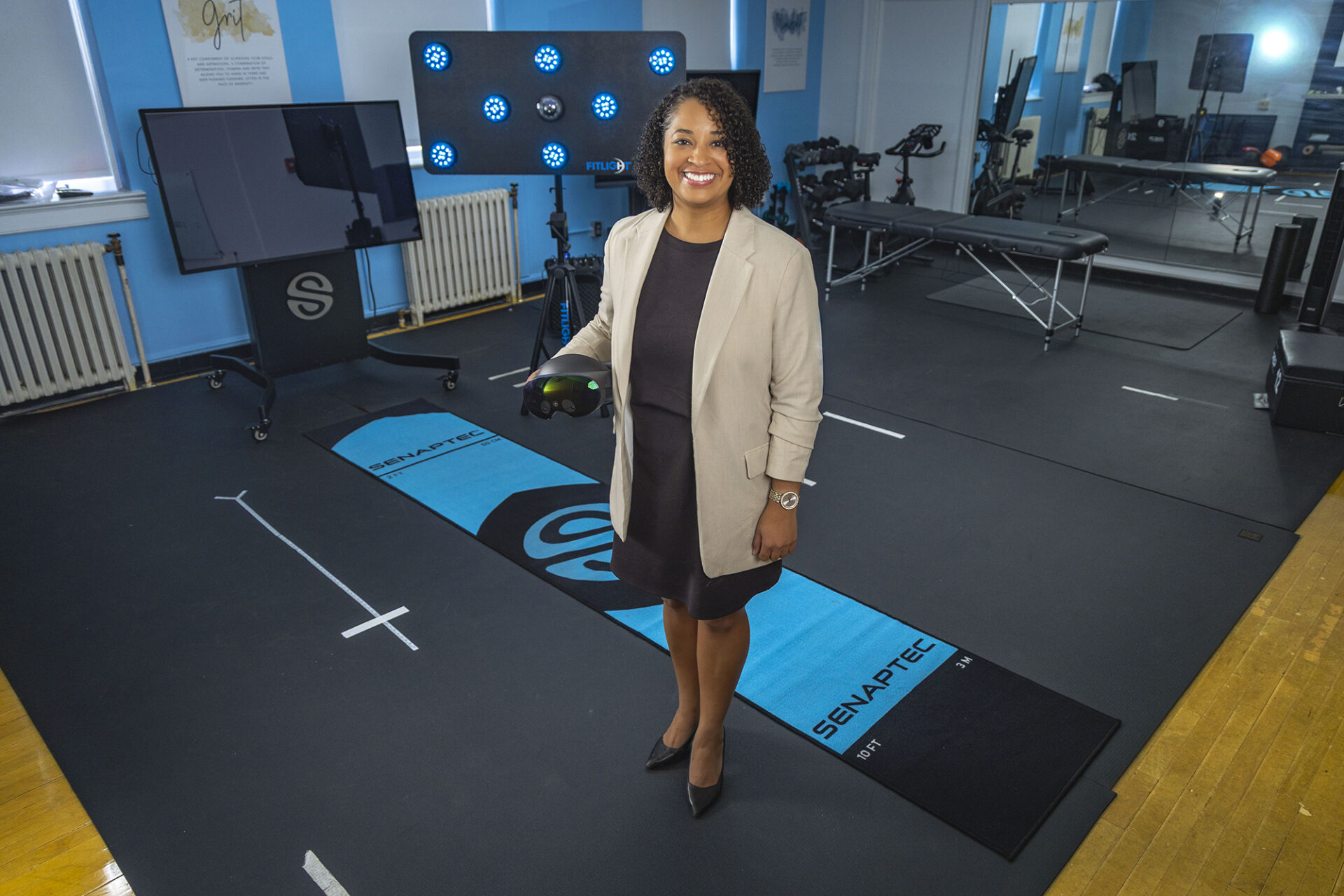 a woman holds a VR headset while standing in her lab