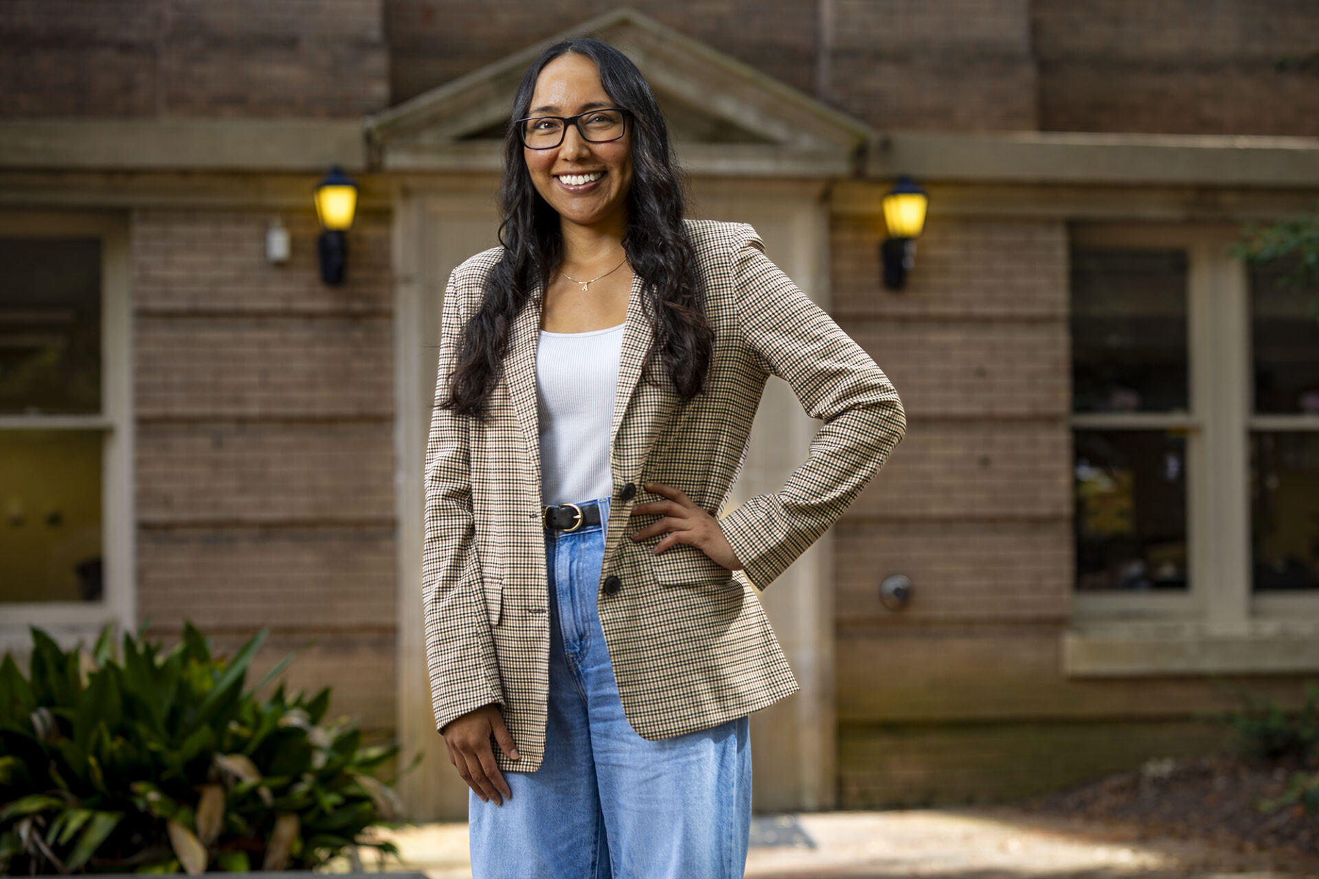 a woman leans against a window which shows her reflection