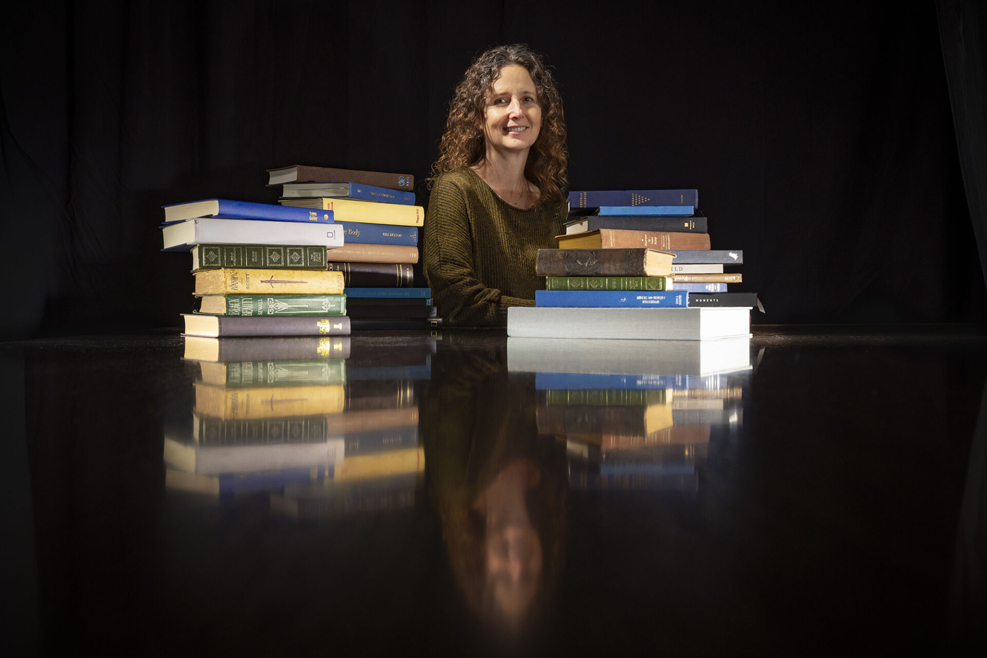 Hilary Lithgow is surrounded by books in a black room