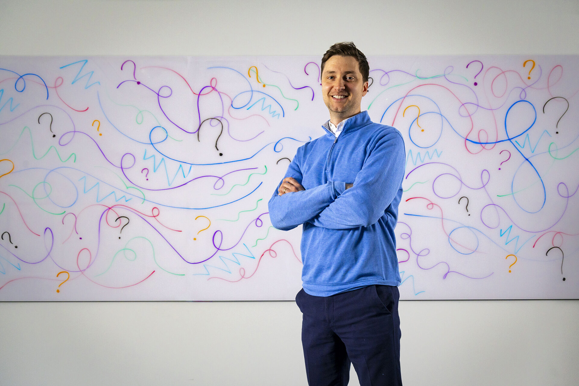 Nicholas Fogleman stands in front of a white board covered in colorful squiggles