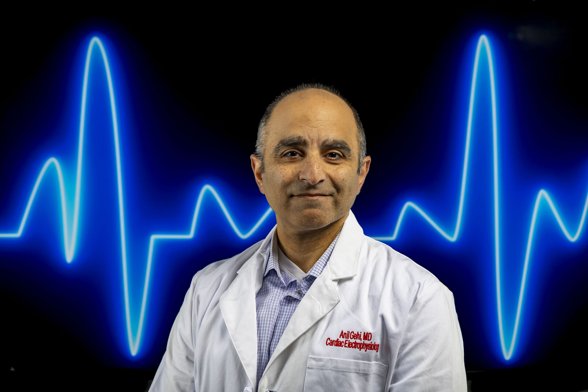 Anil Gehi stands in front of a screen with a heart rate monitor