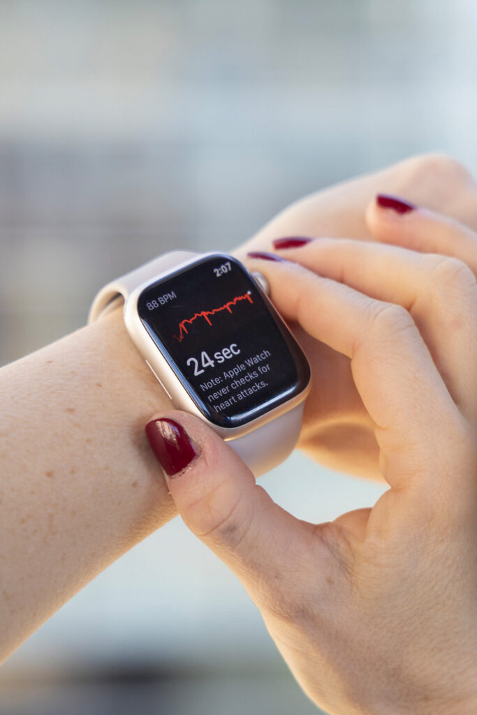 a hand on a smartwatch as it runs an EKG diagnostic