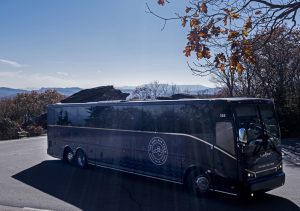 The tour bus photographed on a sunny day, with the Blue Ridge Mountains in the background.